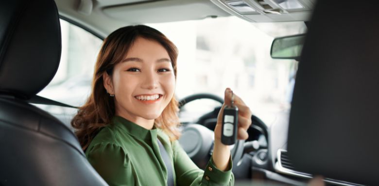 A woman sitting in the front seat of a car, holding a set of keys.