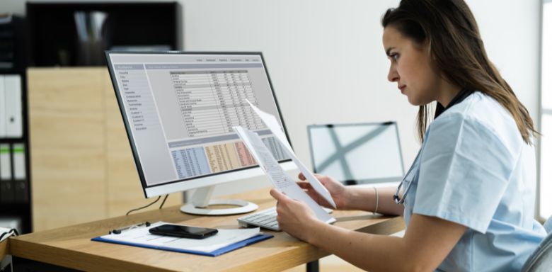 A hospital administrator looking at paperwork in front of a computer.