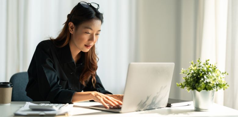 A woman sitting at a desk, using a laptop.