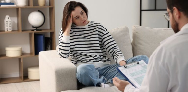 A woman sitting on a couch, talking to a therapist.