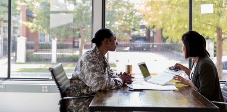 A veteran talking to a woman, showing her different paperwork.