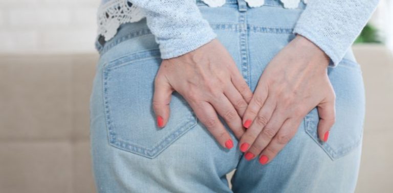 A woman holding both hands over the back of her jeans.