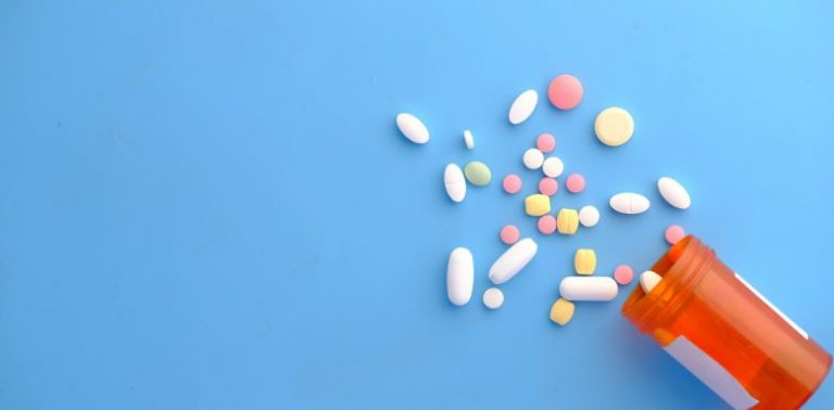A bottle of pills spilling out onto a blue background.