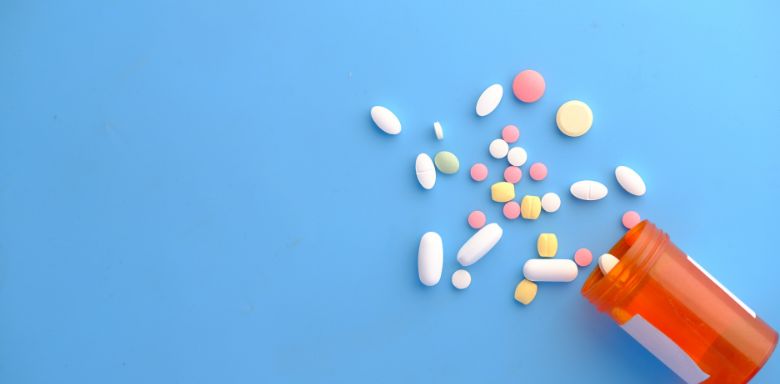 A bottle of pills spilling out onto a blue background.