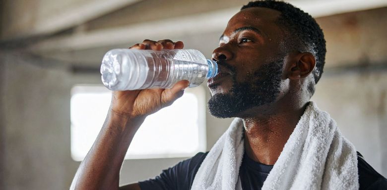 A man drinking from a plastic water bottle during a workout.