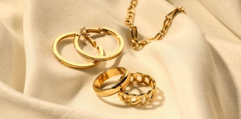 Gold earrings and a gold necklace laid out together.