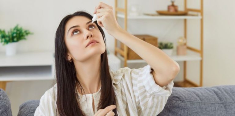 A woman giving herself eyedrops.